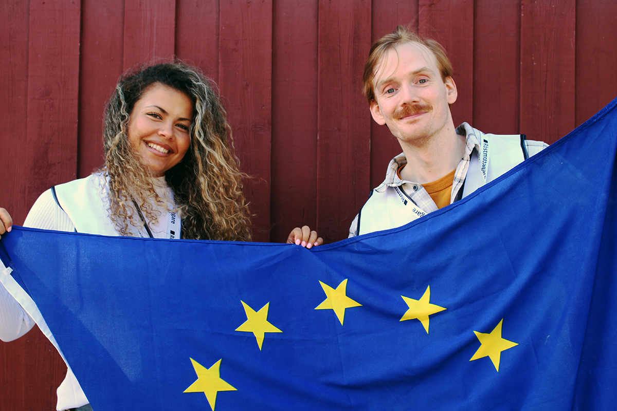 Två valarbetare håller i en EU-flagga.