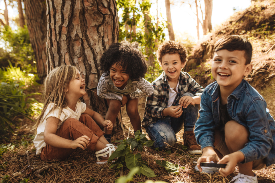 Fyra barn som ler i skogen.