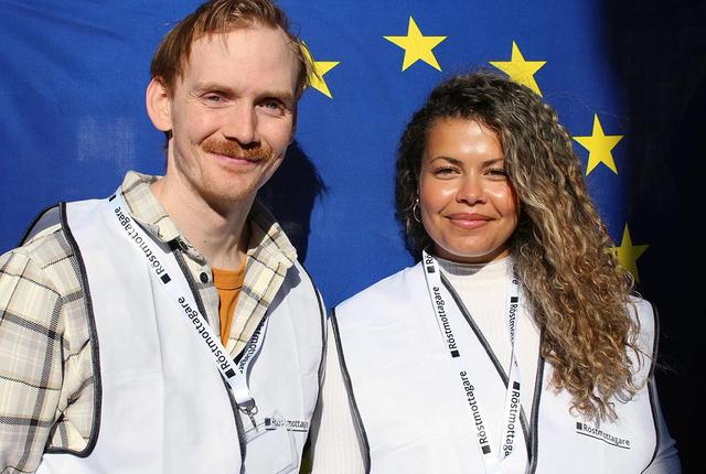 En man och en kvinna står leendes framför en EU-flagga.