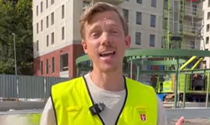 Foto på kommunens projektledare Simon Aspenberg med de nybyggda punkthusen i bakgrunden.