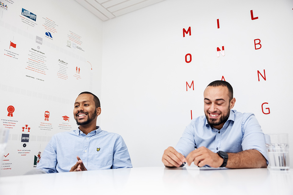 Saleh Karrani och Ali Khalil sitter vid ett bord i företagets kontor och ser glada ut. På väggarna kan man se milstolpar i företagets utveckling.  Foto: Nils Petter Nilsson