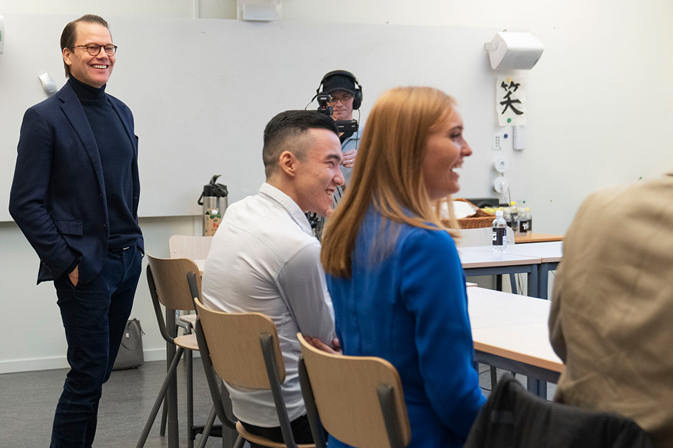 Victoria Högberg och andra gymnasieelever sitter vid ett bord och samtalar. Prins Daniel står bredvid, till vänster på bilden. Foto: Oscar Omne.