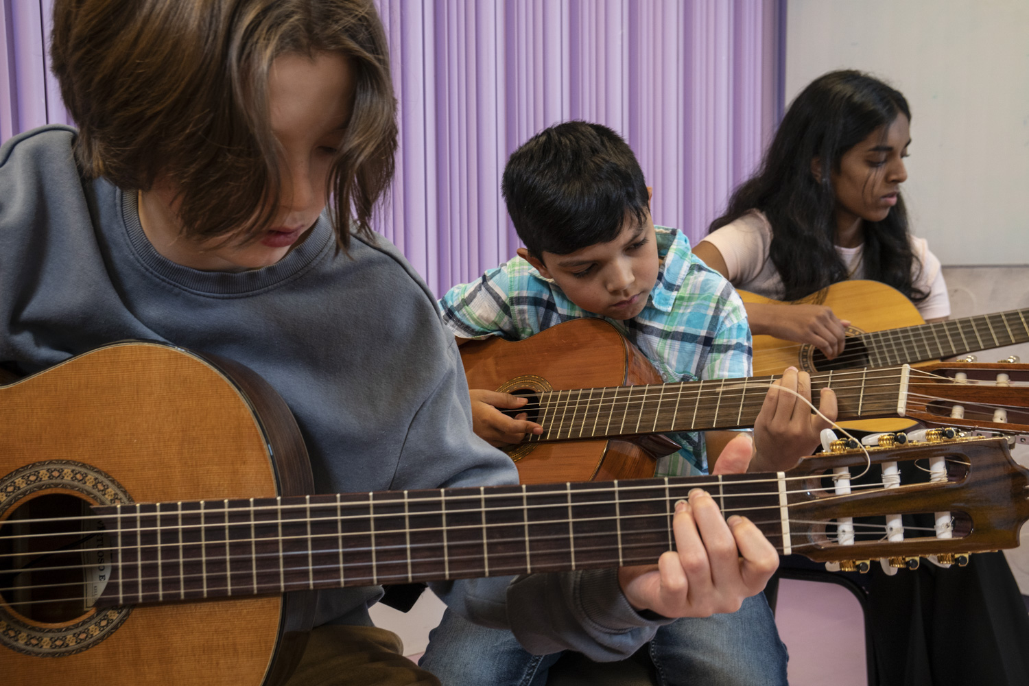 Tre barn som spelar gitarr.