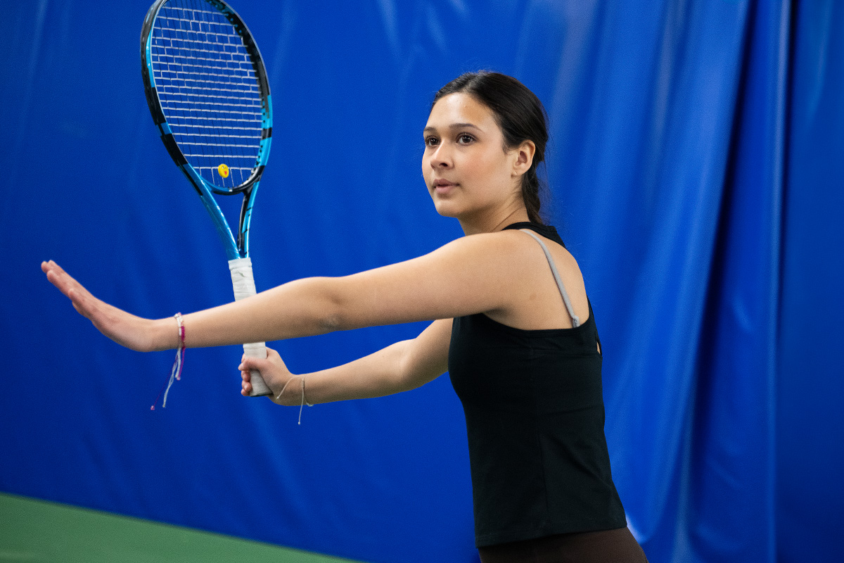 Flicka som spelar tennis.
