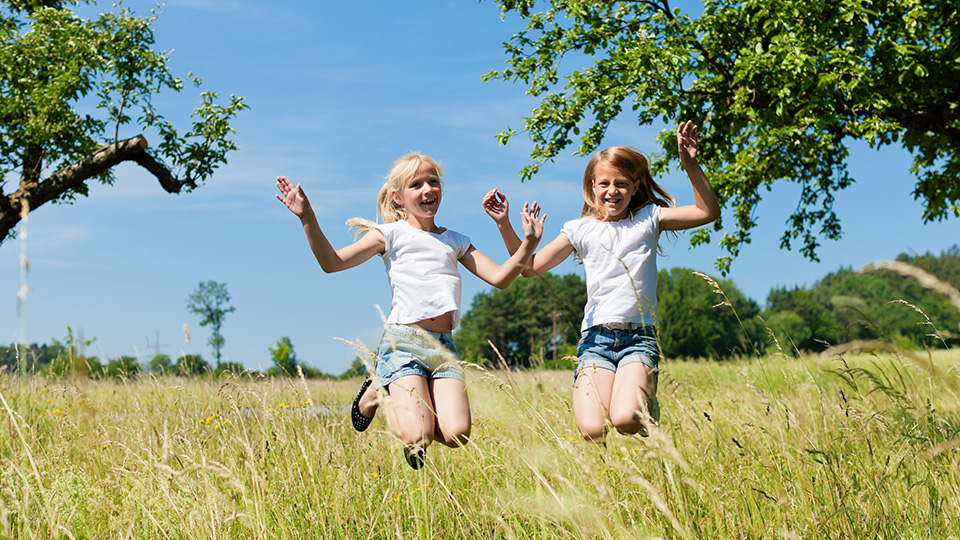 Två barn springer på en sommaräng.