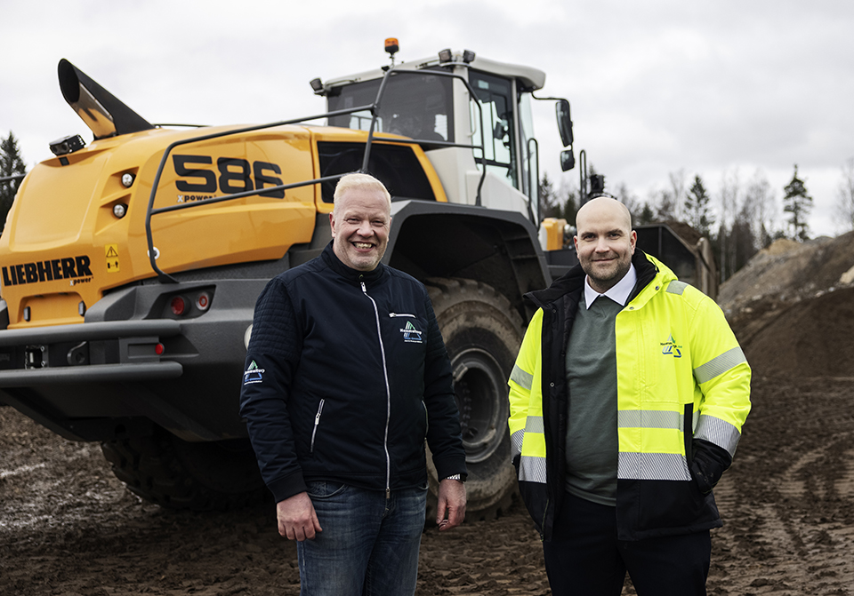 Bröderna Christer och Johannes Otterström i arbetskläder framför en av företagets grävmaskiner.