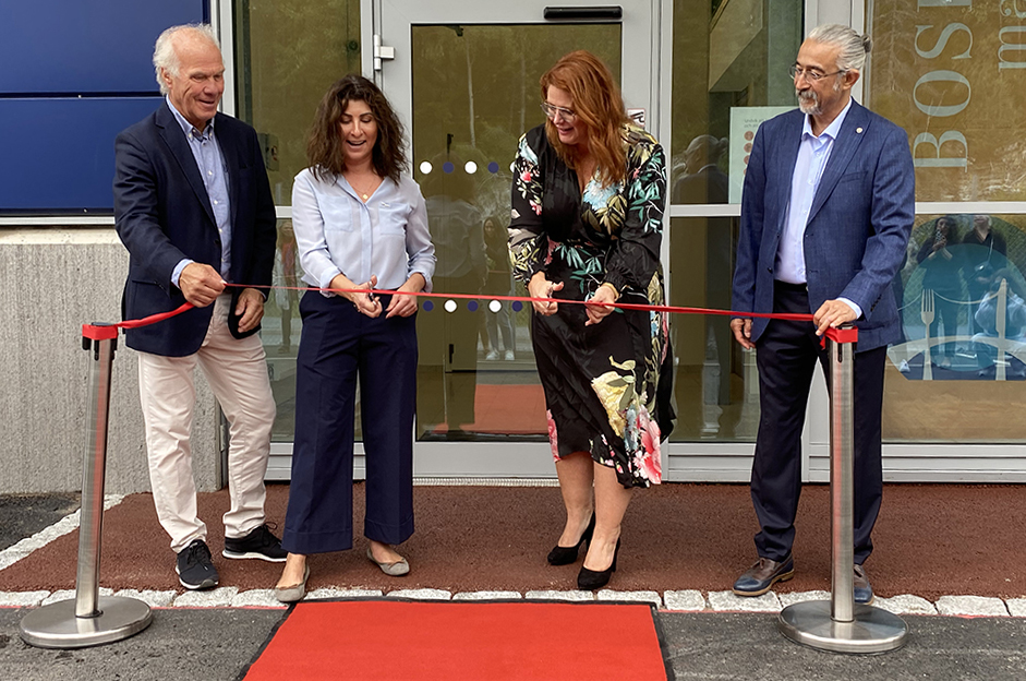 Fyra personer står vid Bosphorus entré till nya matanläggningen framför en röd matta och har just klippt av invigningsbandet. De är glada och uppspelta.