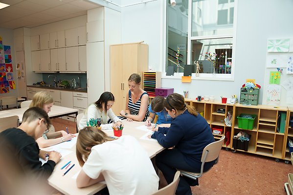 Lärare och elever sitter i ett klassrum och ritar. 
