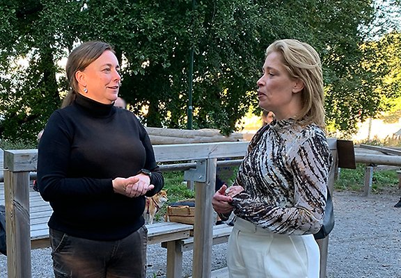 Två kvinnor står utomhus och samtalar