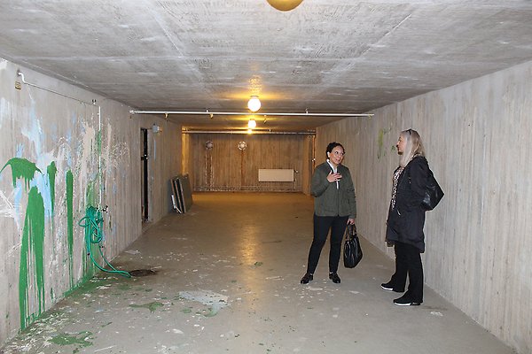 Två kvinnor står och pratar i ett tomt skyddsrum.