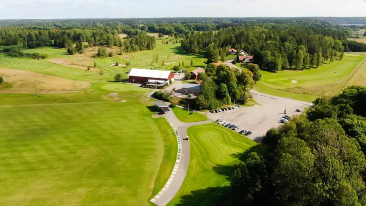 Flygbild över en grön och solig golfbana: